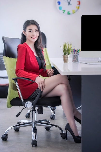 Businesswoman in red suit smiling and sitting in office