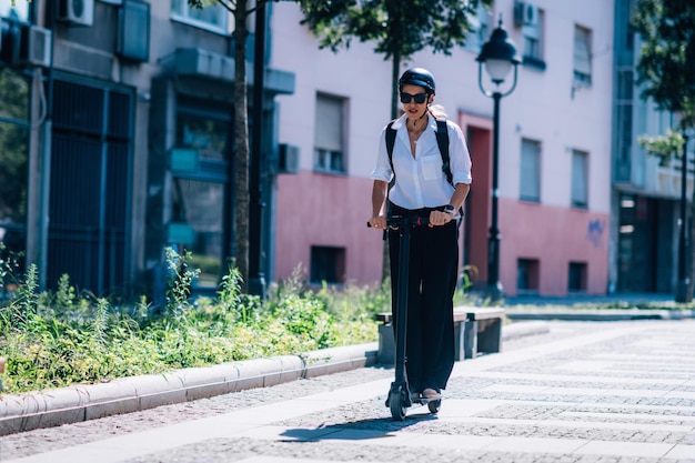 Бизнесменка едет на электрическом скутере в городе