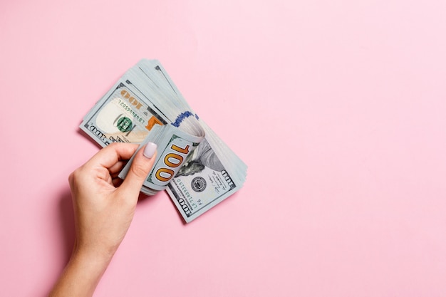 Businesswoman's hands counting one hundred dollar bills on colorful background. Salary and wage concept. Top view of Investment concept