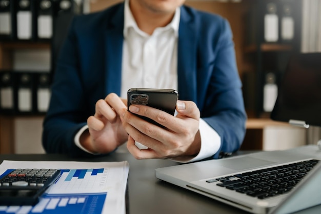 Le mani della donna d'affari che digitano sulla tastiera dello smartphone e del laptop nella luce del mattino computer che digita online in officexa