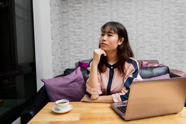 Businesswoman sat in front of the laptop and looked out of the window.