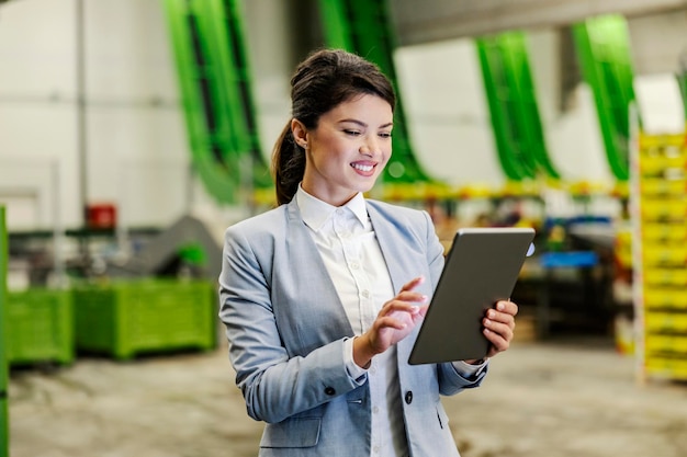 A businesswoman scrolling on tablet in fruit production warehouse