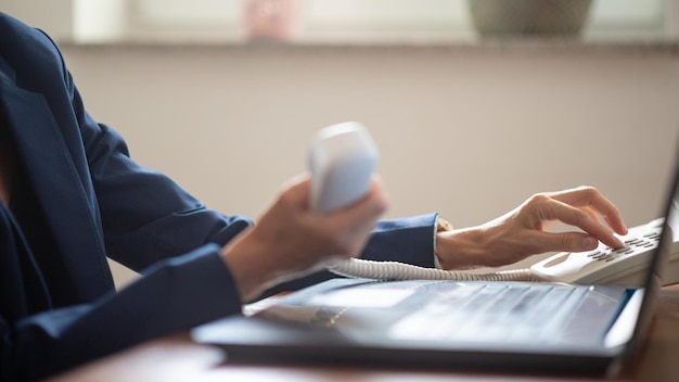 Businesswoman or secretary holding landline telephone receiver dialing a phone number