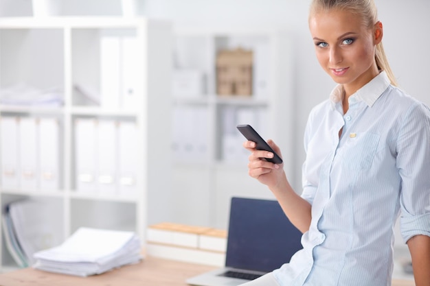 Businesswoman sending message with smartphone in office