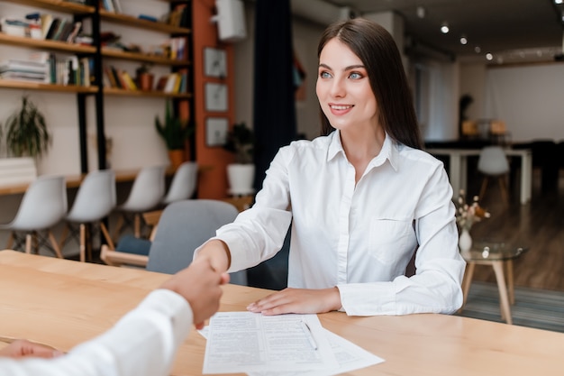 Businesswoman shaking hands on a deal after signing contract