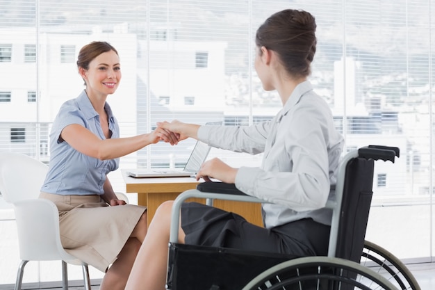 Businesswoman shaking hands with disabled colleague