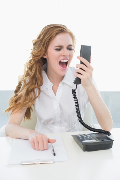 Businesswoman shouting into the phone at office