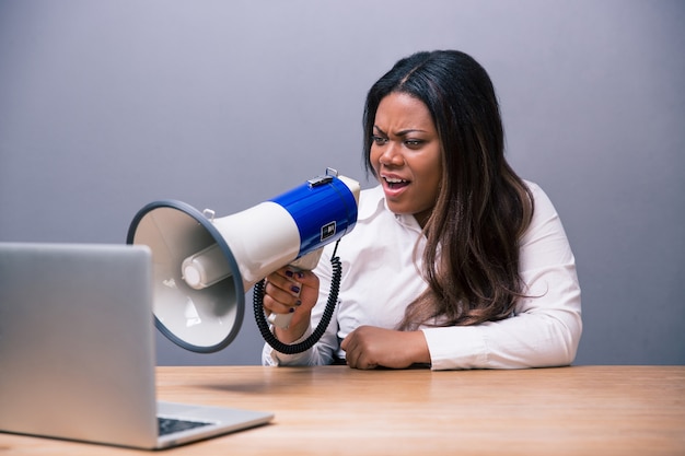 businesswoman shouting in megaphone on laptop