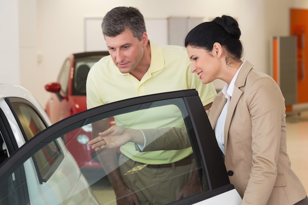 Businesswoman showing a car interior to her customers