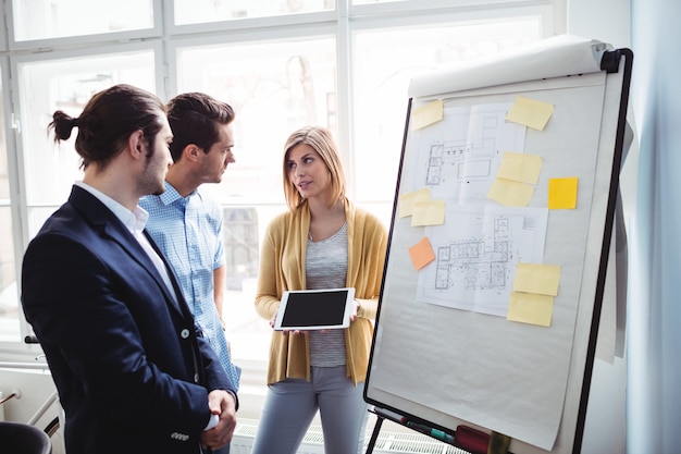 Businesswoman showing digital tablet to coworkers during meeting