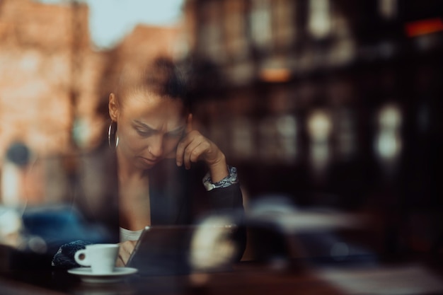 a businesswoman sitting in a cafe on a break and using a tablet