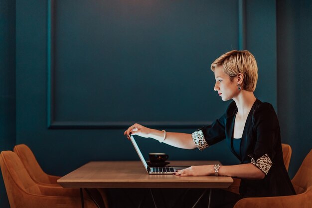 Donna d'affari seduta in un caffè mentre si concentra a lavorare su un portatile e partecipa a una riunione online focalizzazione selettiva foto di alta qualità