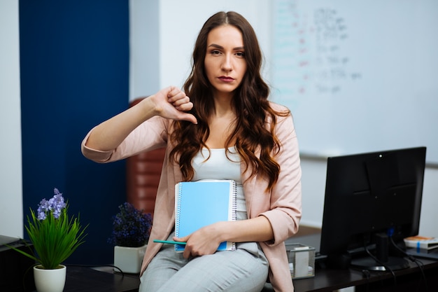 Businesswoman sitting at desk showing thumb down