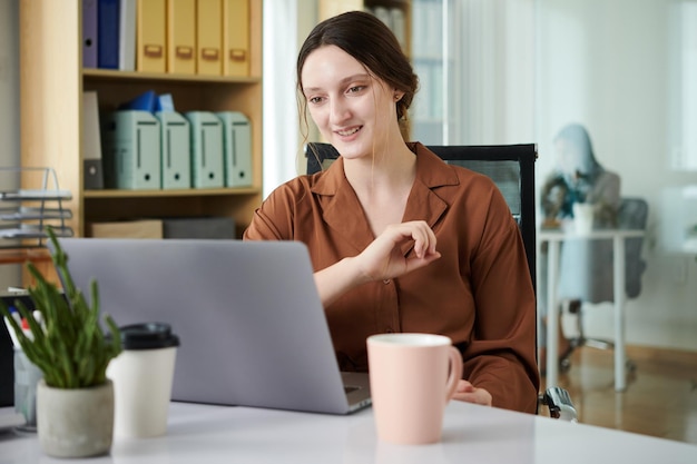 Foto imprenditrice seduta al suo posto di lavoro con il computer portatile