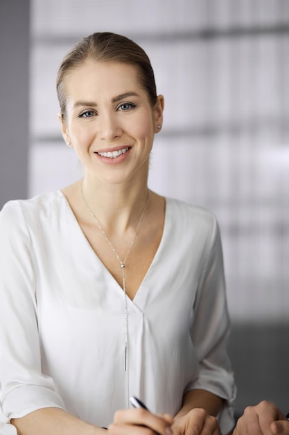 Businesswoman sitting and looking at camera in office. Business headshot.