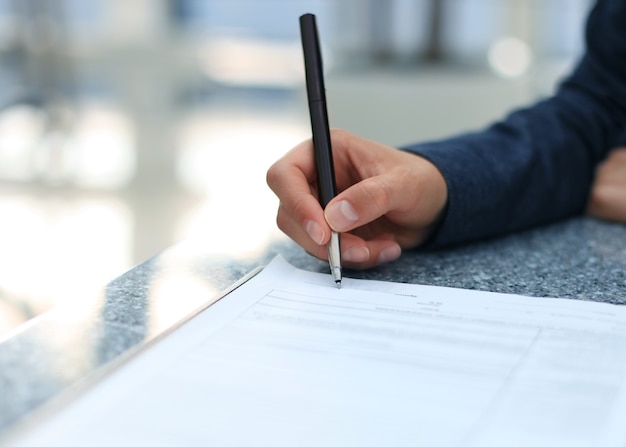 Businesswoman sitting at office desk signing a contract with shallow focus on signature.