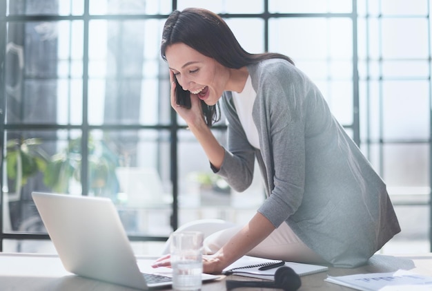 Businesswoman sitting in office talking on the phone