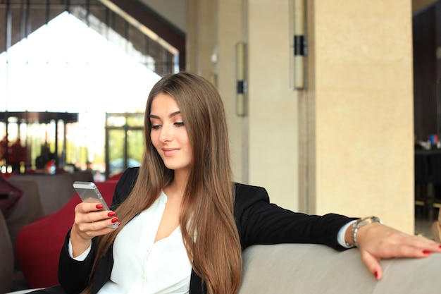 Businesswoman sitting sofa using smartphone in coffee shop.