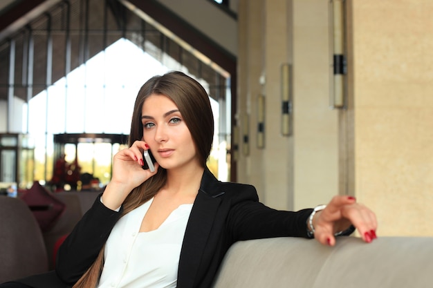 Businesswoman sitting sofa using smartphone in coffee shop.