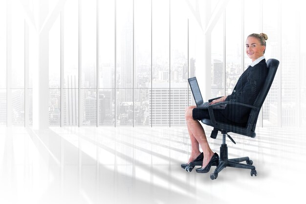 Photo businesswoman sitting on swivel chair with laptop against room with large window looking on city