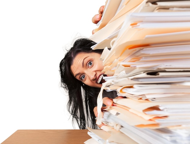 Businesswoman sitting at the table with many papers on background