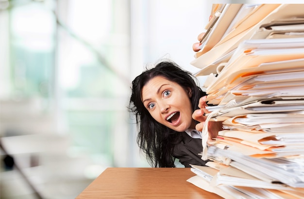 Businesswoman sitting at the table with many papers in office