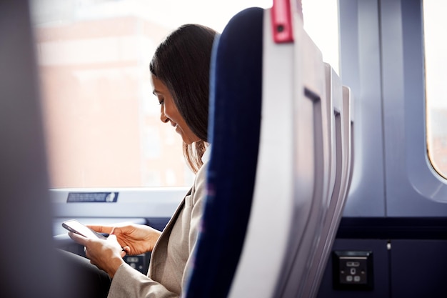 사업가 휴대 전화에서 메시지를 확인 하는 작업에 통근 하는 기차에 앉아