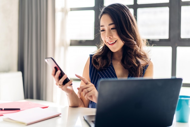 Businesswoman sitting and working with laptop computer and use smartphone.creative business people planning in her workstation at modern work loft