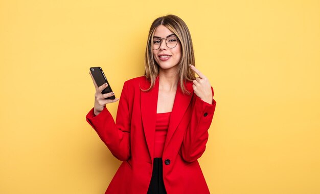 Businesswoman smiling confidently pointing to own broad smile. smartphone concept