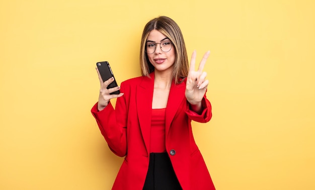 Businesswoman smiling and looking happy, gesturing victory or peace. smartphone concept