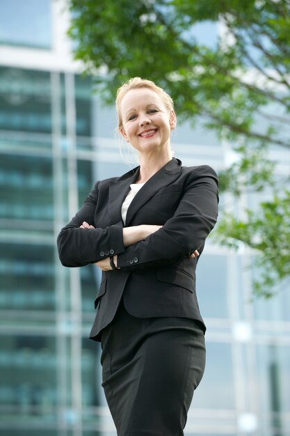 Businesswoman smiling outdoors with arms crossed