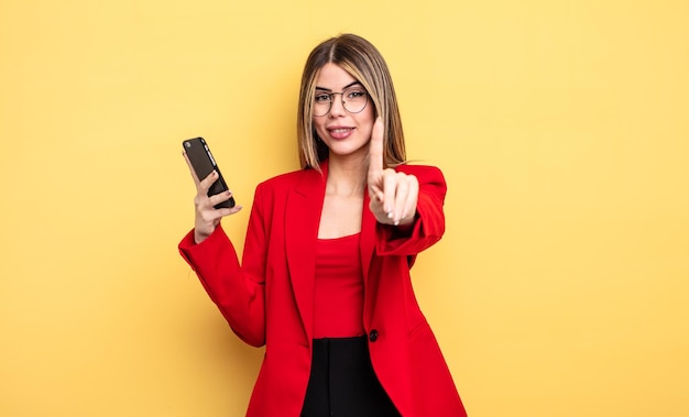 Businesswoman smiling proudly and confidently making number one smartphone concept