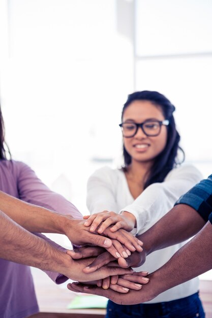 Photo businesswoman stacking hands with team while standing at creative office