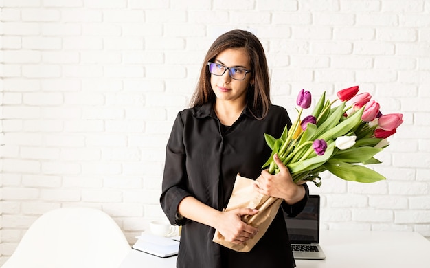 businesswoman standing by the desk with fresh tulips bouquet