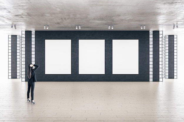 사진 세 개의 빈 광고판이 있는 현대적인 갤러리 내부에 서 있는 사업가