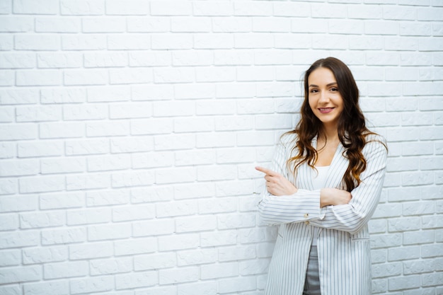 Businesswoman standing near white brick wall