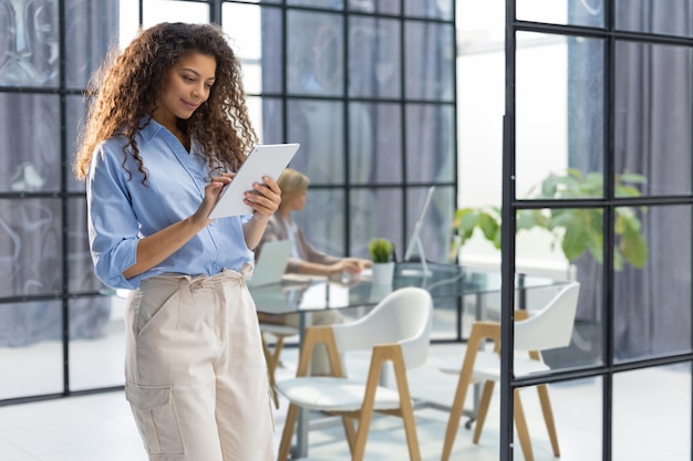 Businesswoman standing in the office corridor with documents Collegue is on the background