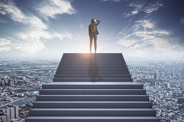 Businesswoman standing at the top of the concrete stairs thinking above the city Future success and growth concept