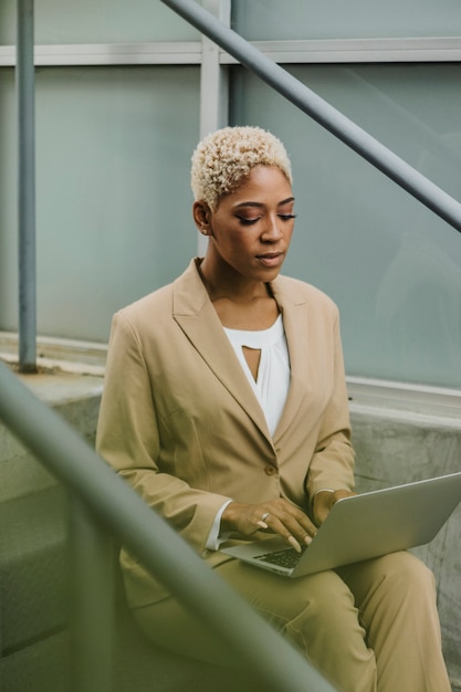 Businesswoman on the steps using her laptop