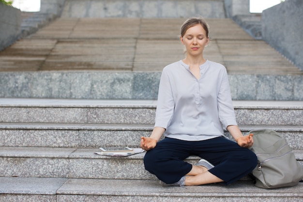 Businesswoman or student meditating on stairs