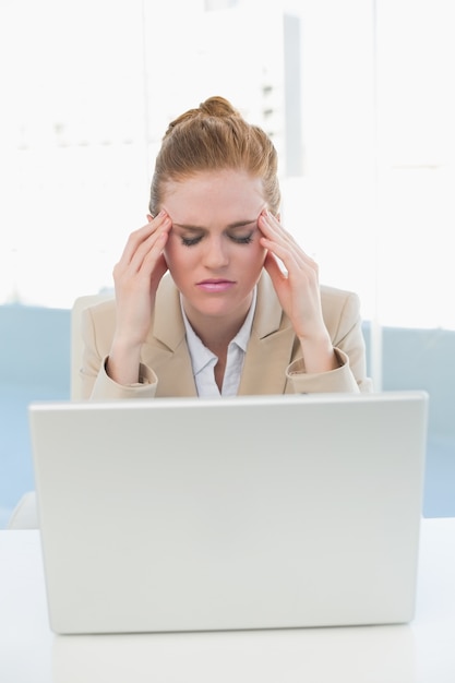 Businesswoman suffering from headache in front of laptop