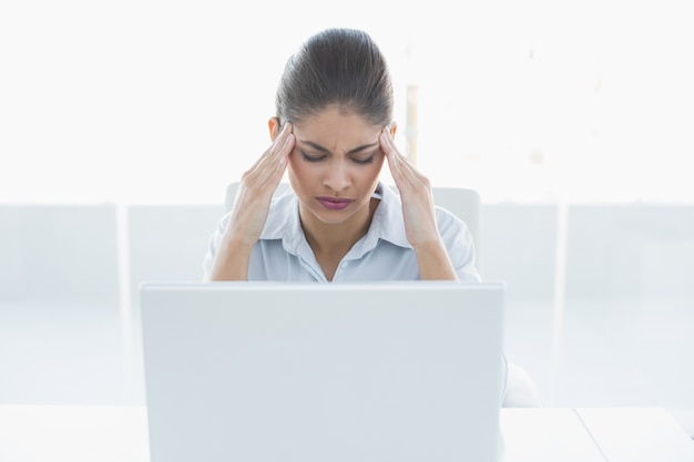 사무실에서 노트북으로 두통으로 고통받는 사업가