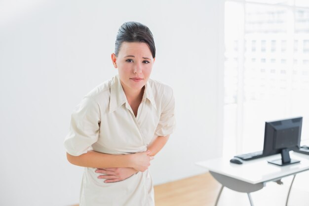 Businesswoman suffering from stomach pain in office