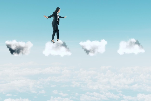 Businesswoman in suit standing on clouds