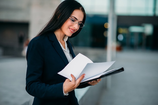 businesswoman in suit works with notebook outdoor, business center. modern financial building, cityscape. 