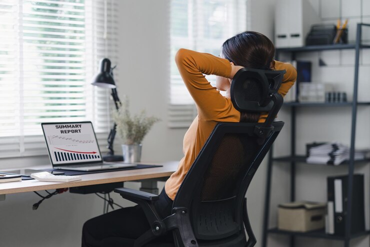 Photo businesswoman taking a break to stretch with a red graph trending downwards in home office