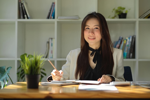 Businesswoman taking notes in her office checking report informations reading paperworks