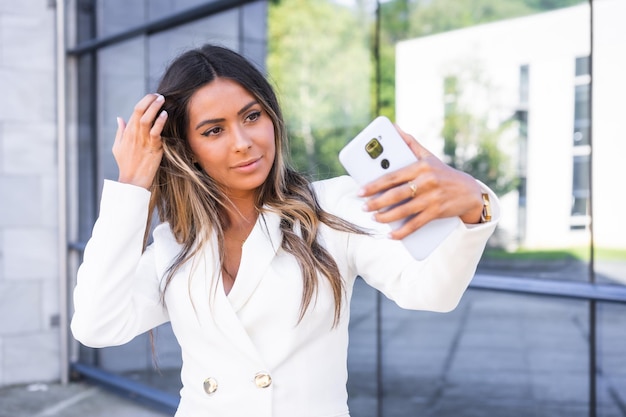 Businesswoman taking selfie with the mobile phone outside a financial building