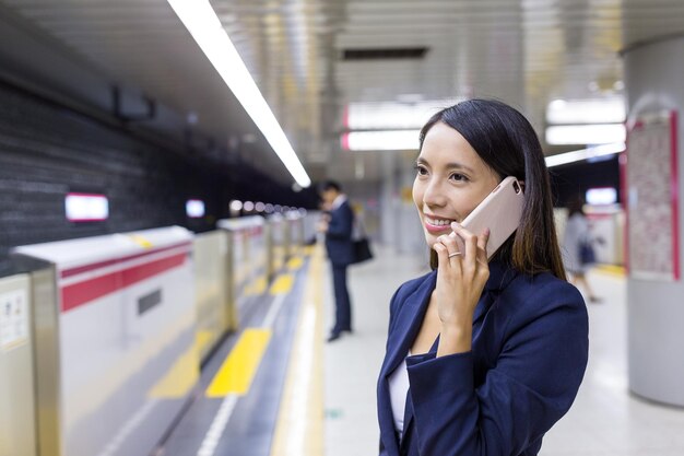 Businesswoman talk to cellphone in train station