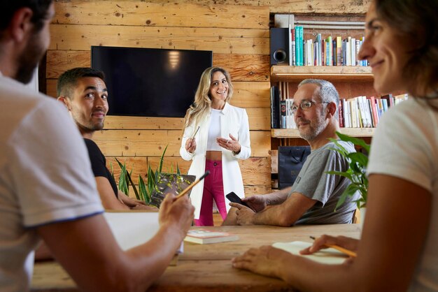 Photo businesswoman talking to her team in the office team building